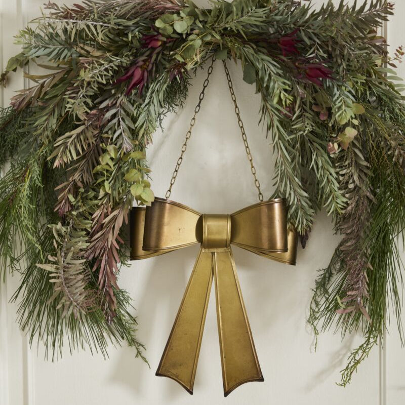 Decorative wreath with a gold bow on a white door