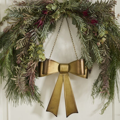 Decorative wreath with a gold bow on a white door