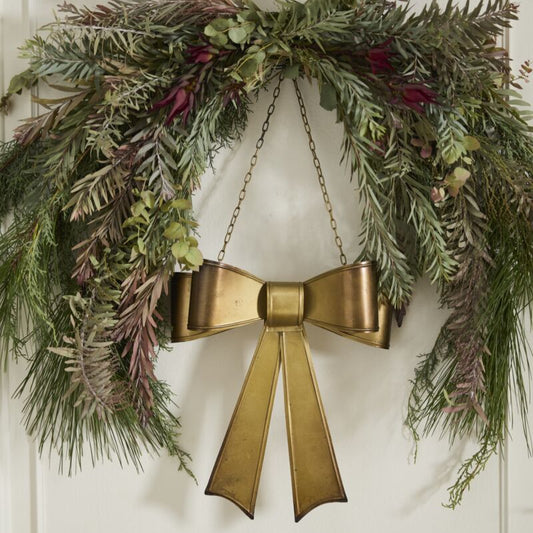 Decorative wreath with a gold bow on a white door