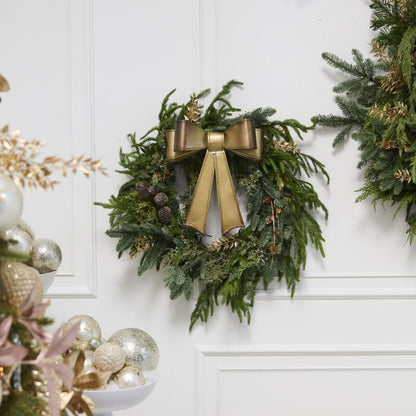 Decorative wreaths with gold bows on a white wall