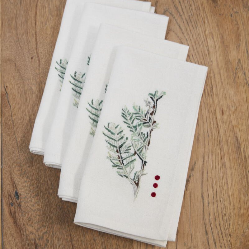 Set of white napkins with green leaf patterns on a wooden surface