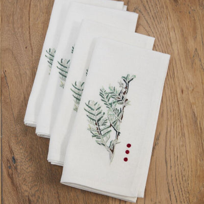 Set of white napkins with green leaf patterns on a wooden surface