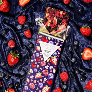 Chocolate bar with strawberries, raspberries and blueberries on a velvet background