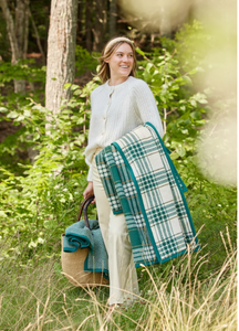 Evergreen Plaid Blanket held by woman walking in field 