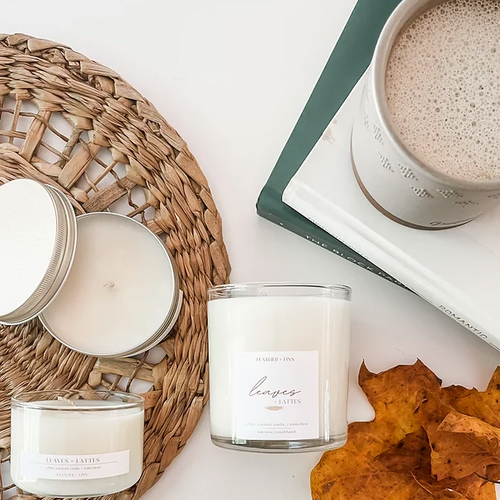 Feather + Finn Leaves and Lattes  tumbler Candle displayed with a mug of coffe, leaves, and all 3 sizes options 