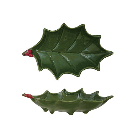 Two green holly leaf-shaped dishes on a white background