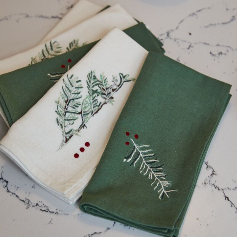 Set of green and white embroidered napkins on a marble surface