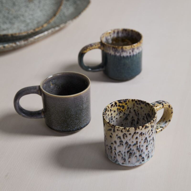 Three ceramic mugs with speckled patterns on a light surface