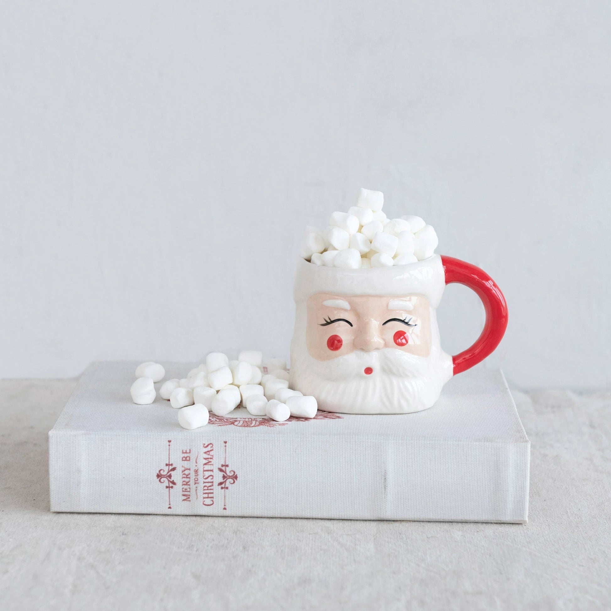 Santa Claus mug with marshmallows on a clear stand against a light gray background