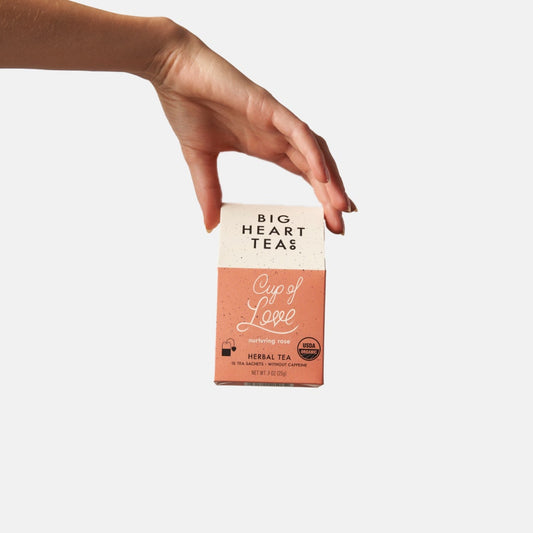 Womans Hand holding this Pink and White Tea Box 