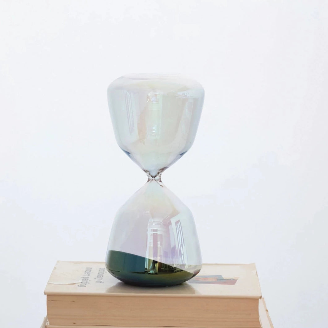 iridescent hourglass with black sand on book