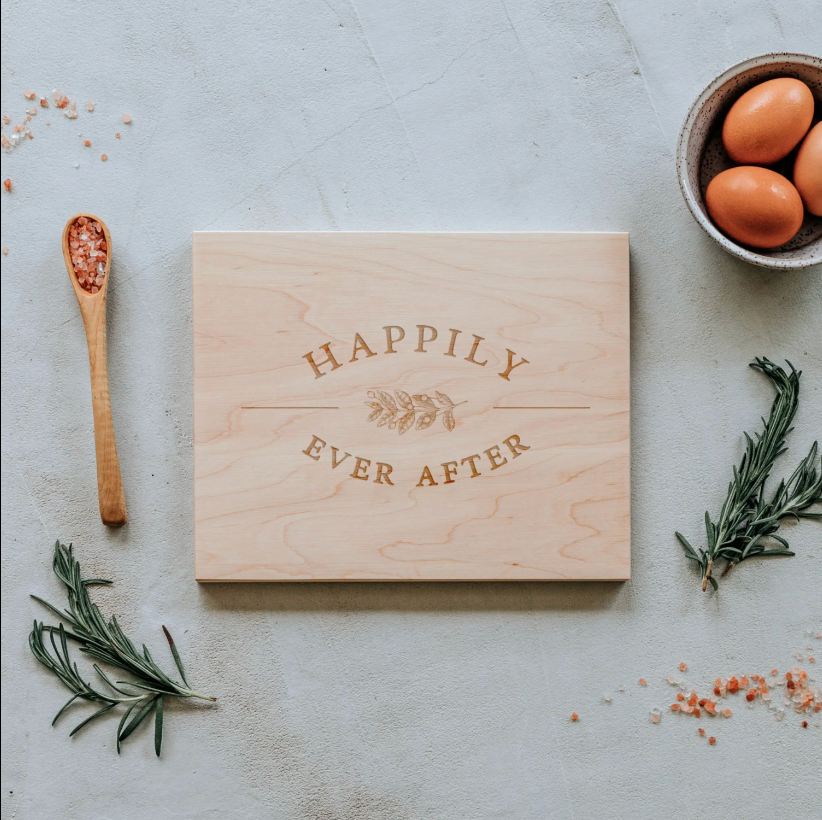 Happily Ever After Cutting Board featured on Maple Wood with etched saying and decorative spring of greenery through center