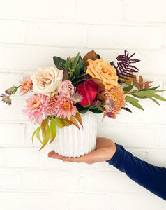 Person holding a colorful + Unique arrangement of flowers 