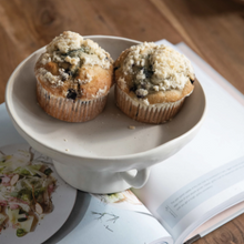 Load image into Gallery viewer, Bowl holding Blueberry Crumble Muffins on a cookbook 
