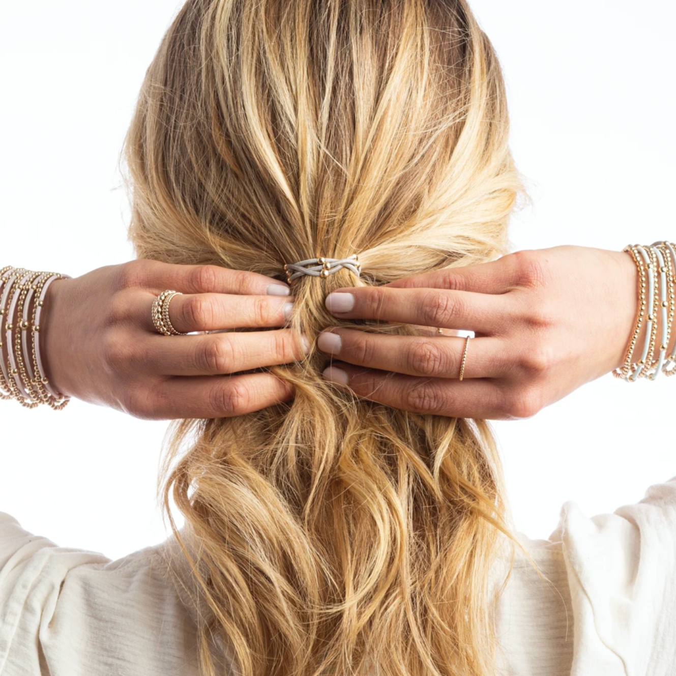 enewton Essential Bracelet + Hair Tie Set in blonde woman putting her hair in a ponytail